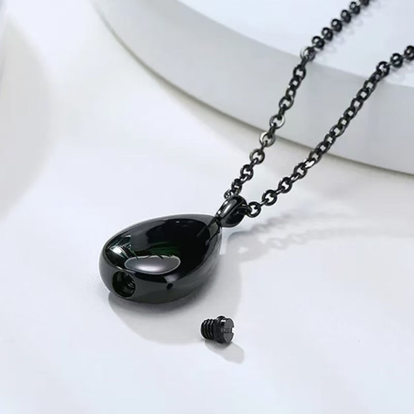 Black teardrop urn pendant opened to show screw-top compartment and closure detail