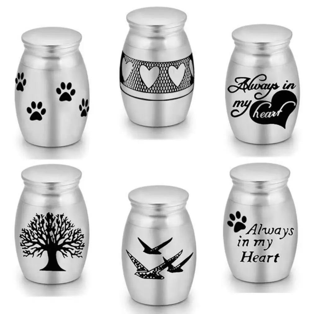 Stainless steel mini pet keepsake urn design options including paw prints, “Always in My Heart,” hearts band, tree, and birds