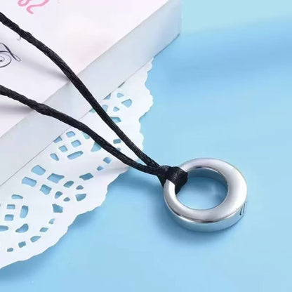Close-up of silver hollow circle urn pendant on adjustable black cord necklace