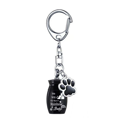 Black Rainbow Bridge pet memorial ashes urn keychain with paw charm on white background, single item