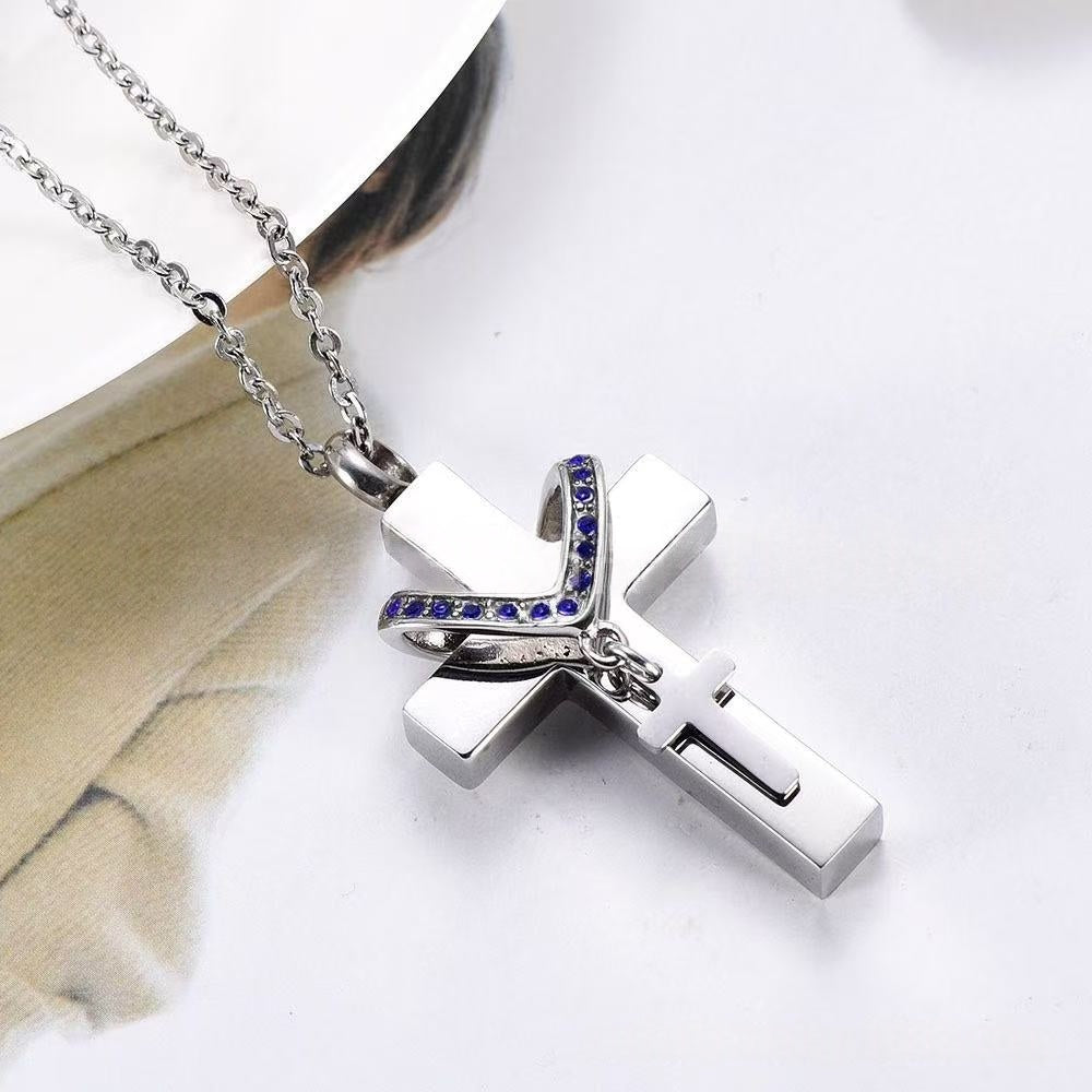 Close-up of stainless steel cross memorial pendant with blue birthstone crystals