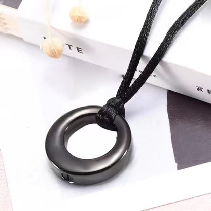 Black hollow circle memorial pendant necklace lifestyle photo on display surface
