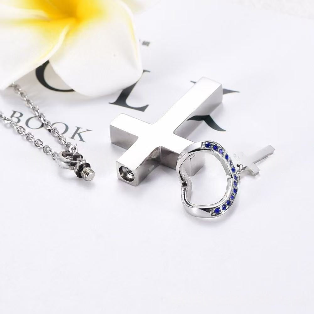 Stainless steel cross urn necklace parts shown with screw compartment and birthstone crystal heart accent
