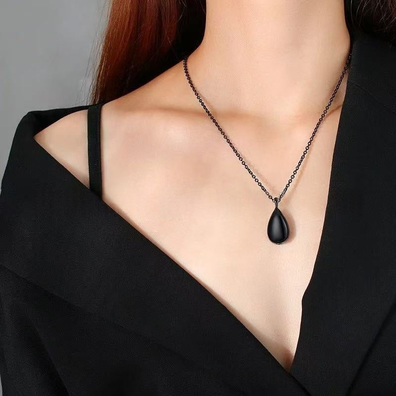 Model wearing black teardrop ashes urn necklace on a chain for minimalist memorial jewelry look