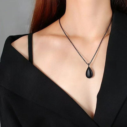 Model wearing black teardrop ashes urn necklace on a chain for minimalist memorial jewelry look