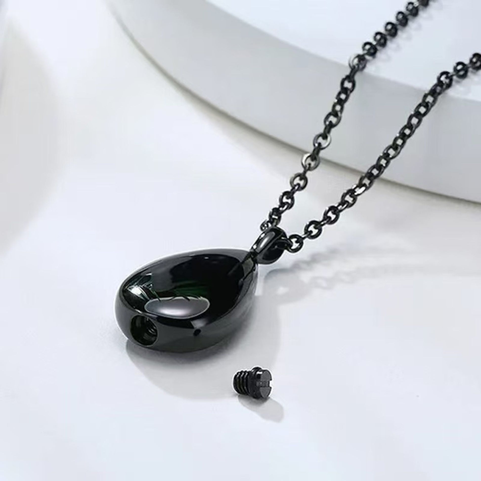 Black teardrop urn pendant opened to show screw-top compartment and closure detail