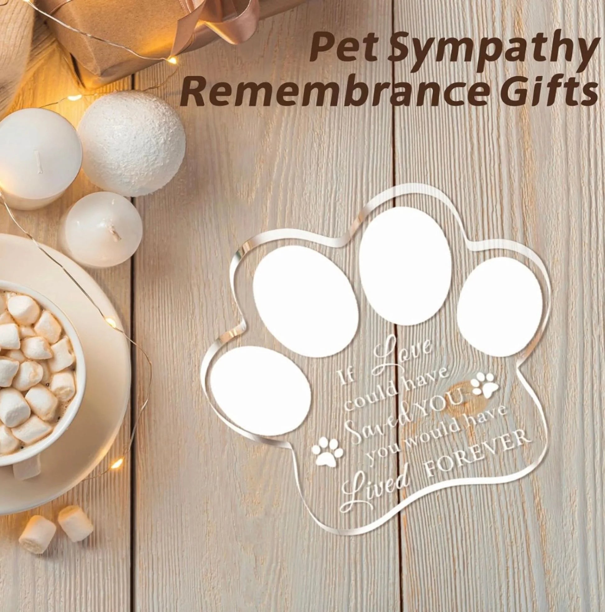 Freestanding clear paw-print acrylic dog memorial plaque displayed with candles and warm lights on a wooden table.