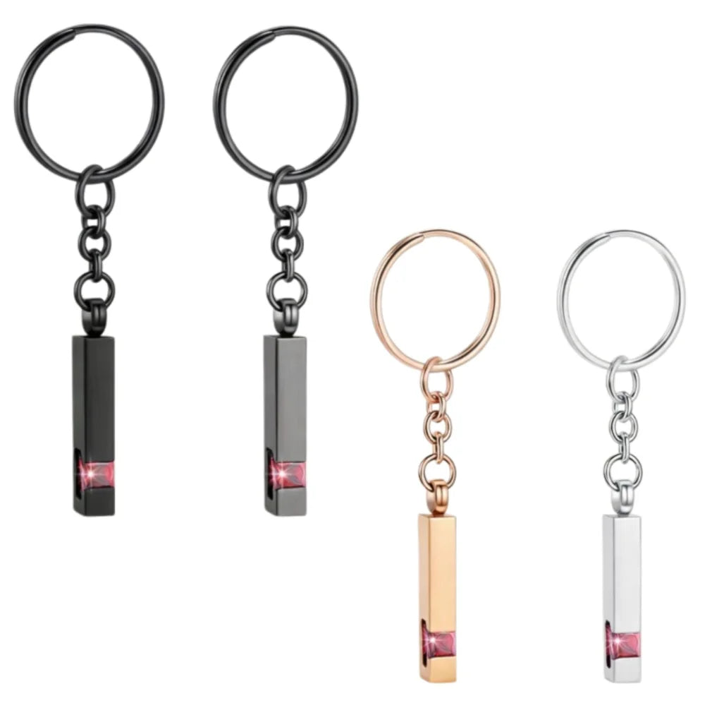 Pet memorial Urn keychain featuring a paw print design, available in black, silver, and rose gold colors. Comes with small tools (funnel, needle) for easy use, ideal for holding small keepsakes like pet fur or ashes.