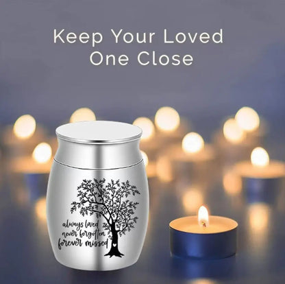 
Silver Tree of Life pet keepsake urn displayed on a table beside candles and a pet photo frame
