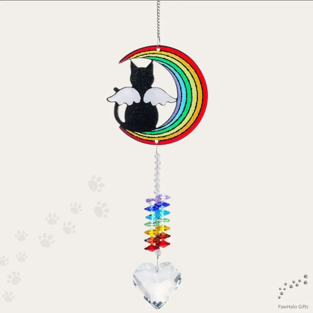 An angel moon cat memorial suncatcher hanging in front of a neutral background.