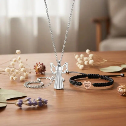 Angel pendant necklace displayed with black cord bracelet on wooden table