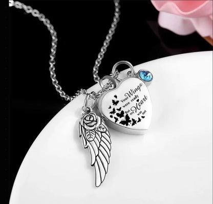 An angel wings heart pet urn necklace sitting elegantly next to a rose flower.