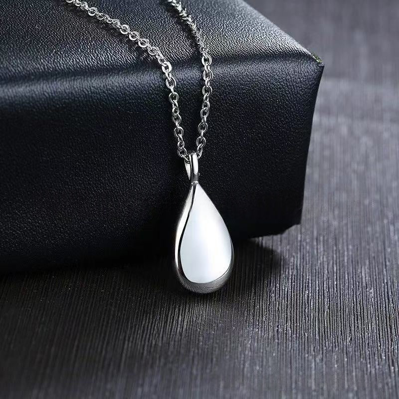 Silver teardrop memorial urn necklace displayed on a black gift box