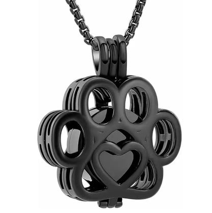 Front close-up view of the black hollow paw print pet memorial keepsake pendant with fine filigree details.