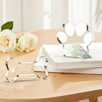 Freestanding acrylic pet memorial plaques in paw and bone shapes on a table.