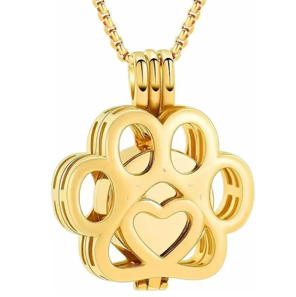 Front close-up view of the gold hollow paw print pet memorial keepsake pendant with fine filigree details.