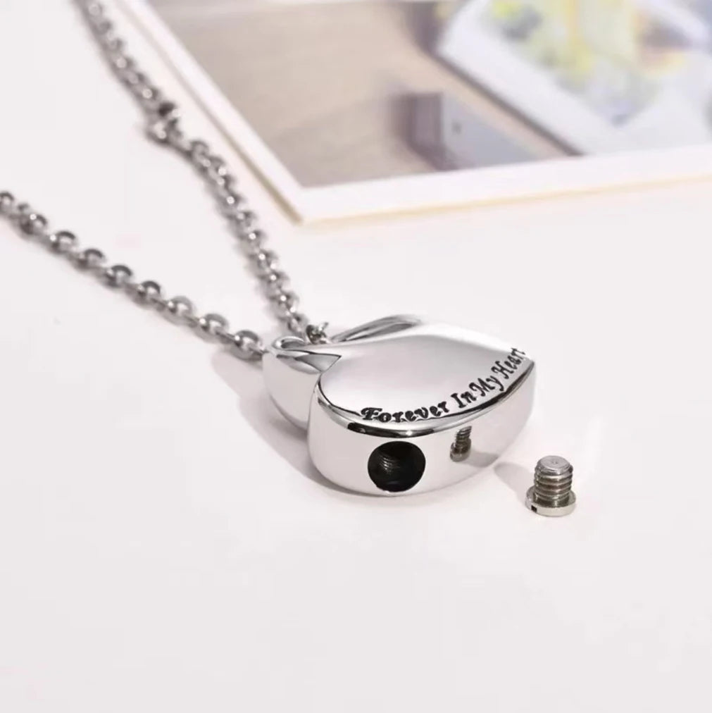 Demonstration showing how to unscrew the hidden bottom screw of the heart keepsake pendant and fill it using steel refilling tools.