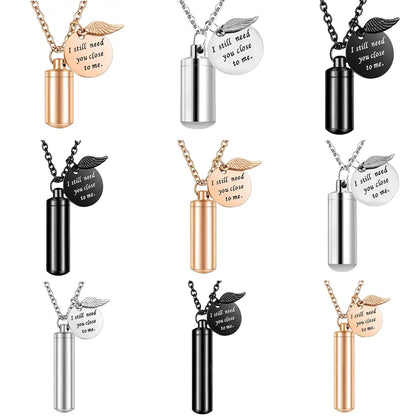 Minimalist cylinder pet urn necklace in silver, gold, and black colors with angel wing charms.
