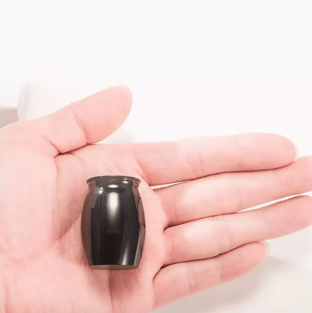 Discreet and palm-sized black pet memorial urn held in a hand to show its lightweight portable scale.
