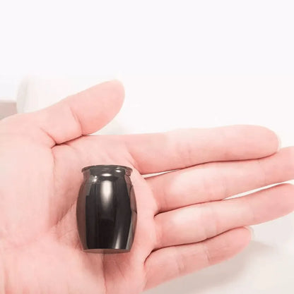 Discreet and palm-sized black pet memorial urn held in a hand to show its lightweight portable scale.