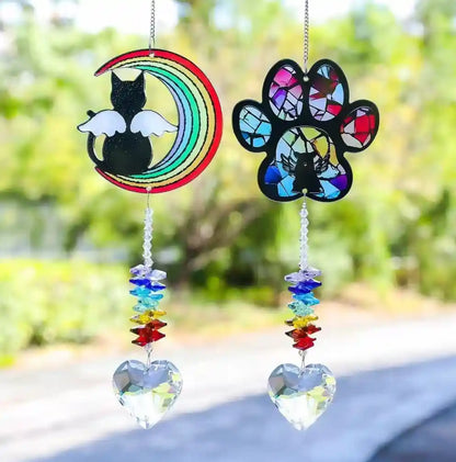Two pet memorial suncatchers hanging outside casting rainbows in natural warm sunlight.
